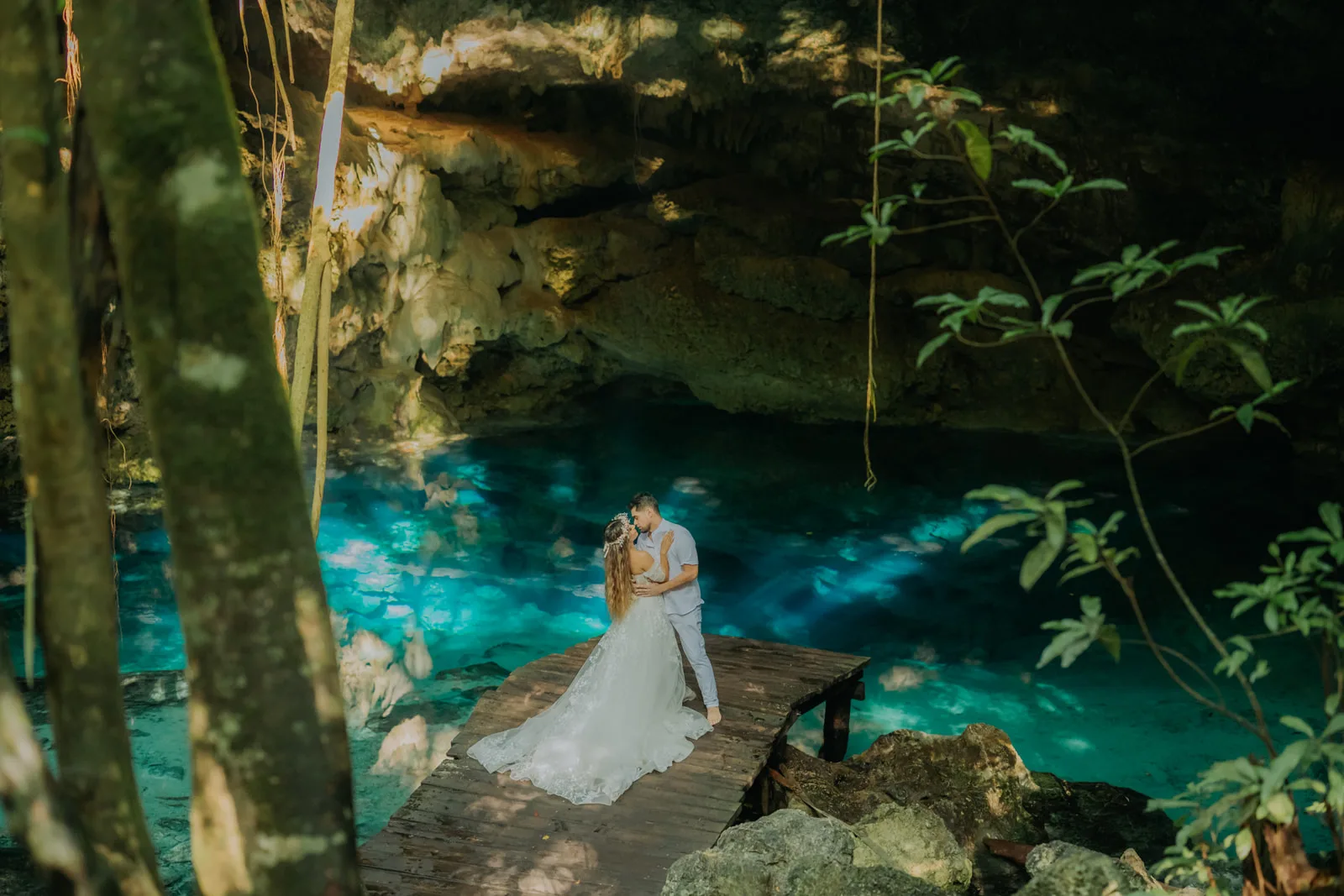 Pareja sobre un muelle de madera frente al agua del cenote